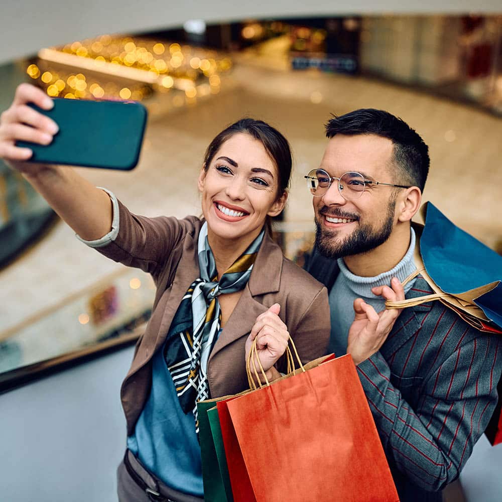 Young happy couple taking selfie while shopping at mall.